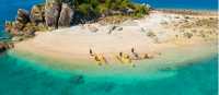Sea kayaking group beaches kayaks on a granite islet, Whitsunday Islands, Queensland.